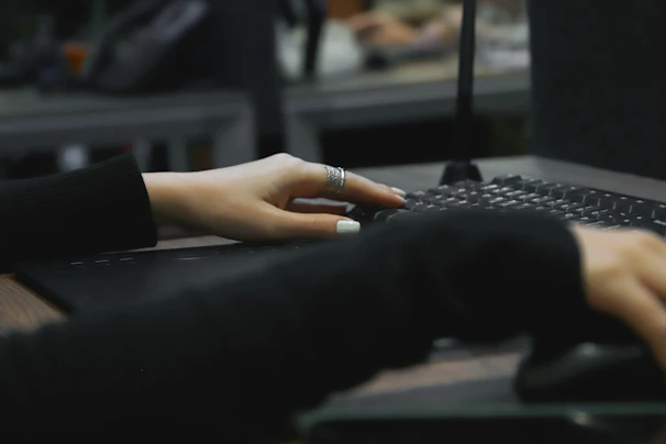 A close-up of hands typing swiftly on a laptop keyboard with a bright, inviting workspace in the background.