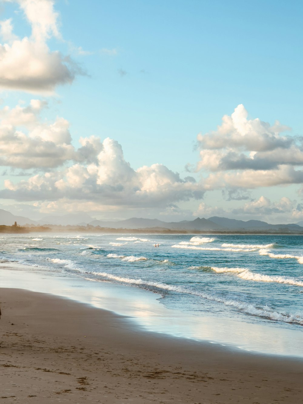 a person walking on the beach with a surfboard