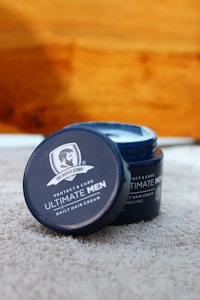 A jar of daily hair cream for men is placed open on a soft, textured surface. The product label features the brand 'The Beard Story' and emphasizes protection and care, indicating it is paraben-free.