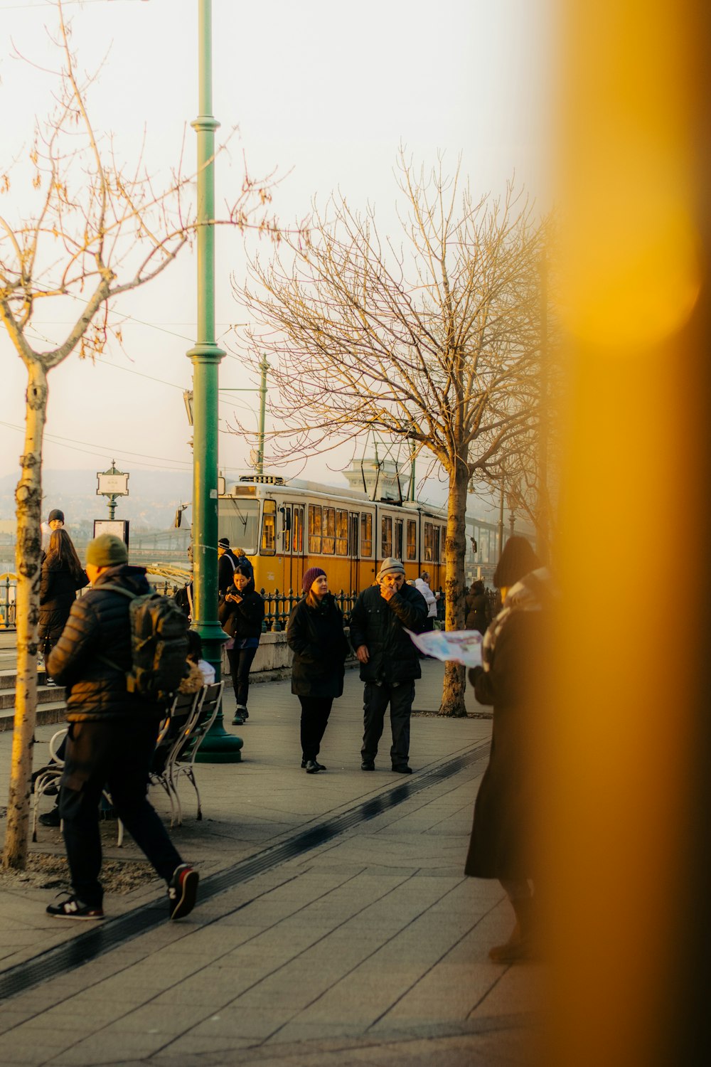 a group of people walking down a sidewalk next to a train