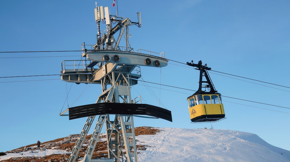 a yellow and black ski lift going up a snowy hill