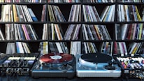 Close-up of vinyl records and DJ equipment on a minimalist desk.