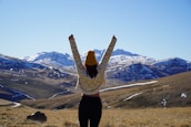 A peaceful scene of a person standing on a rocky peak, arms raised, wearing a 4110 apparel co hoodie.