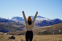 A peaceful scene of a person standing on a rocky peak, arms raised, wearing a 4110 apparel co hoodie.