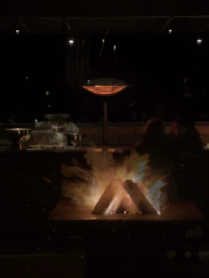 A nighttime scene showing the fire pit glowing warmly beside a picnic setup.