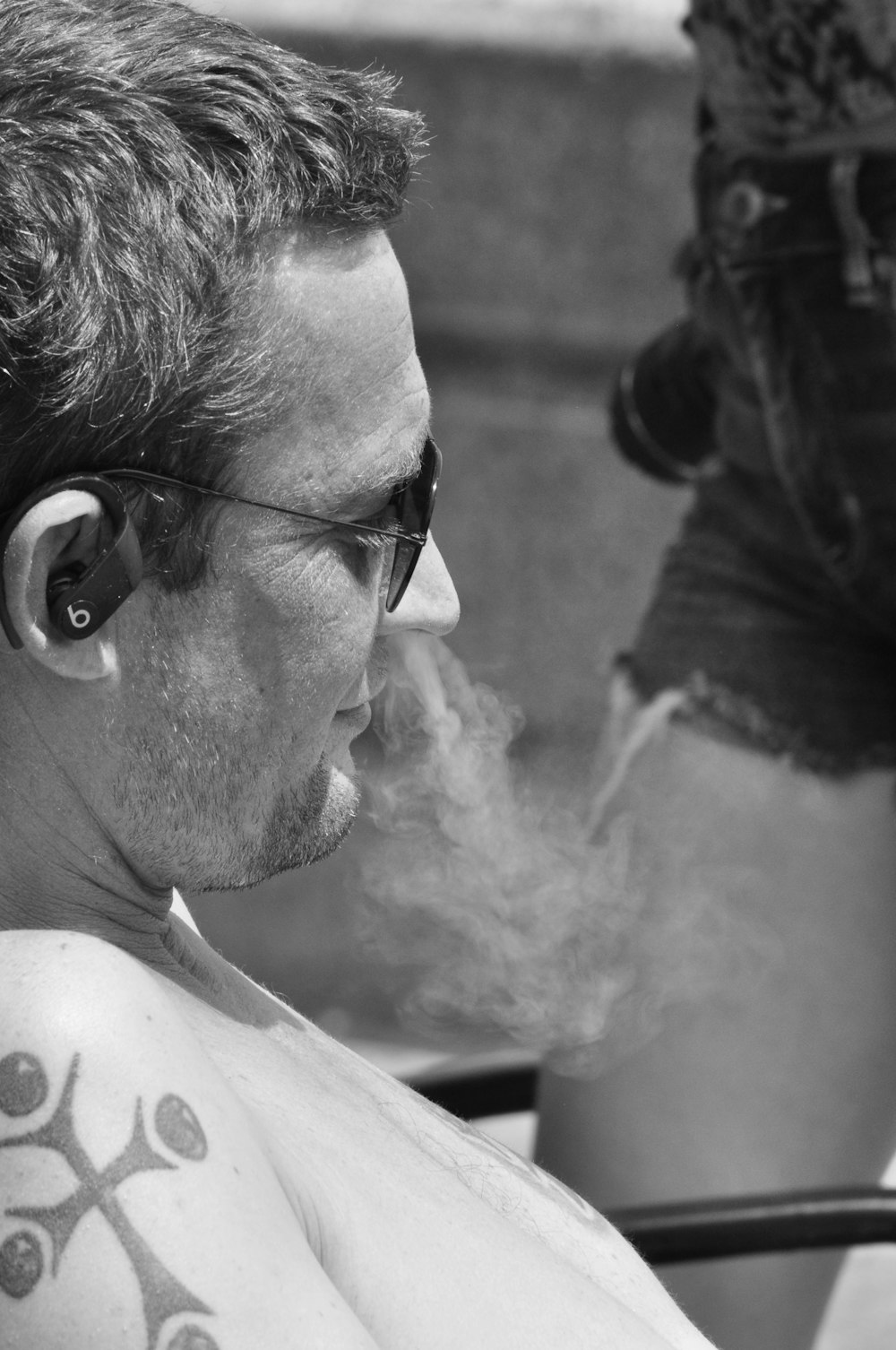 a man with a cross tattoo smoking a cigarette