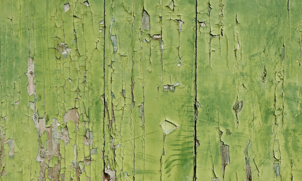 a close up of a green wall with peeling paint