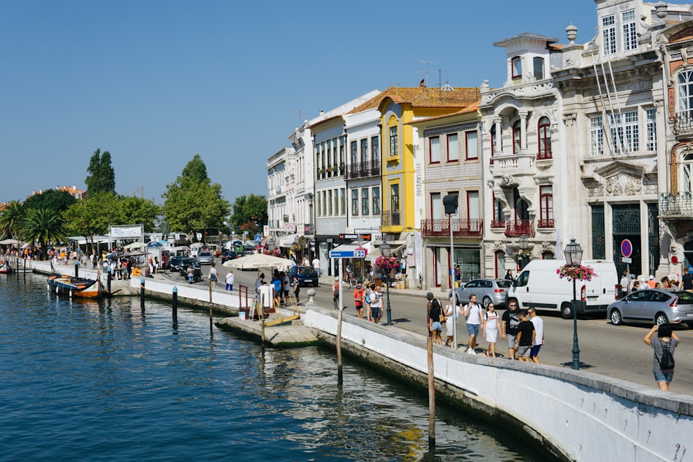 a group of people walking down a street next to a body of water