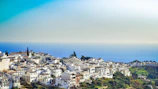 A serene coastal village with turquoise waters and whitewashed buildings.