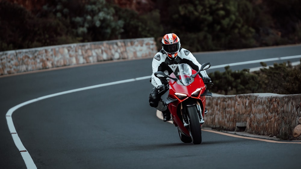 a man riding a red motorcycle down a curvy road