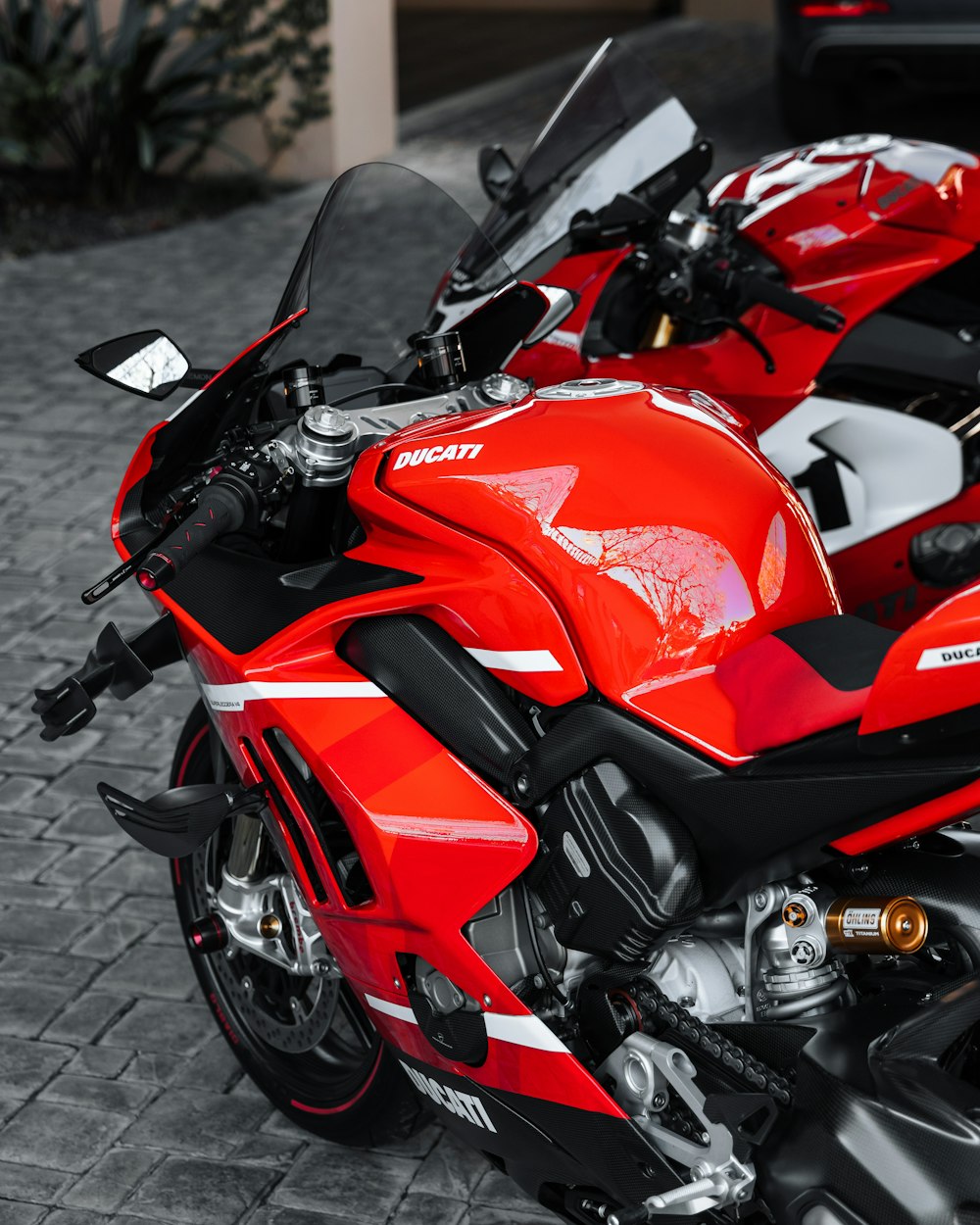 a red motorcycle parked on a brick road