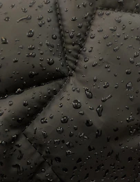 Close-up of reinforced seams and articulated joints on a full-body rain suit in a heavy downpour.