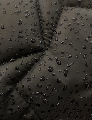 Close-up of waterproof blackout curtain fabric with water droplets beading on the surface.