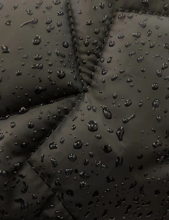 Close-up of a raincoat’s waterproof fabric with raindrops beading on the surface, showcasing pluvipaws quality.