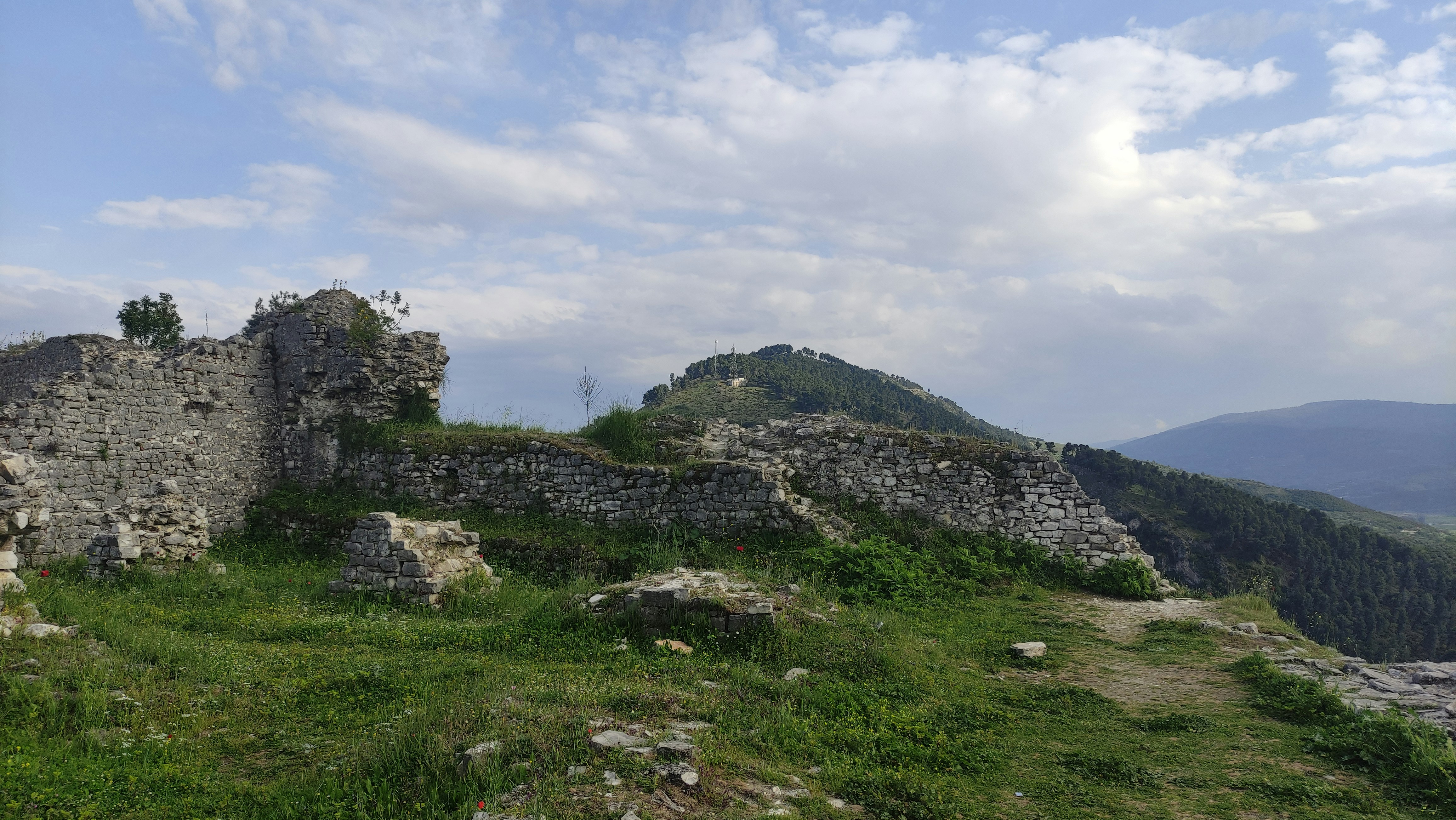 a stone castle sitting on top of a lush green hillside