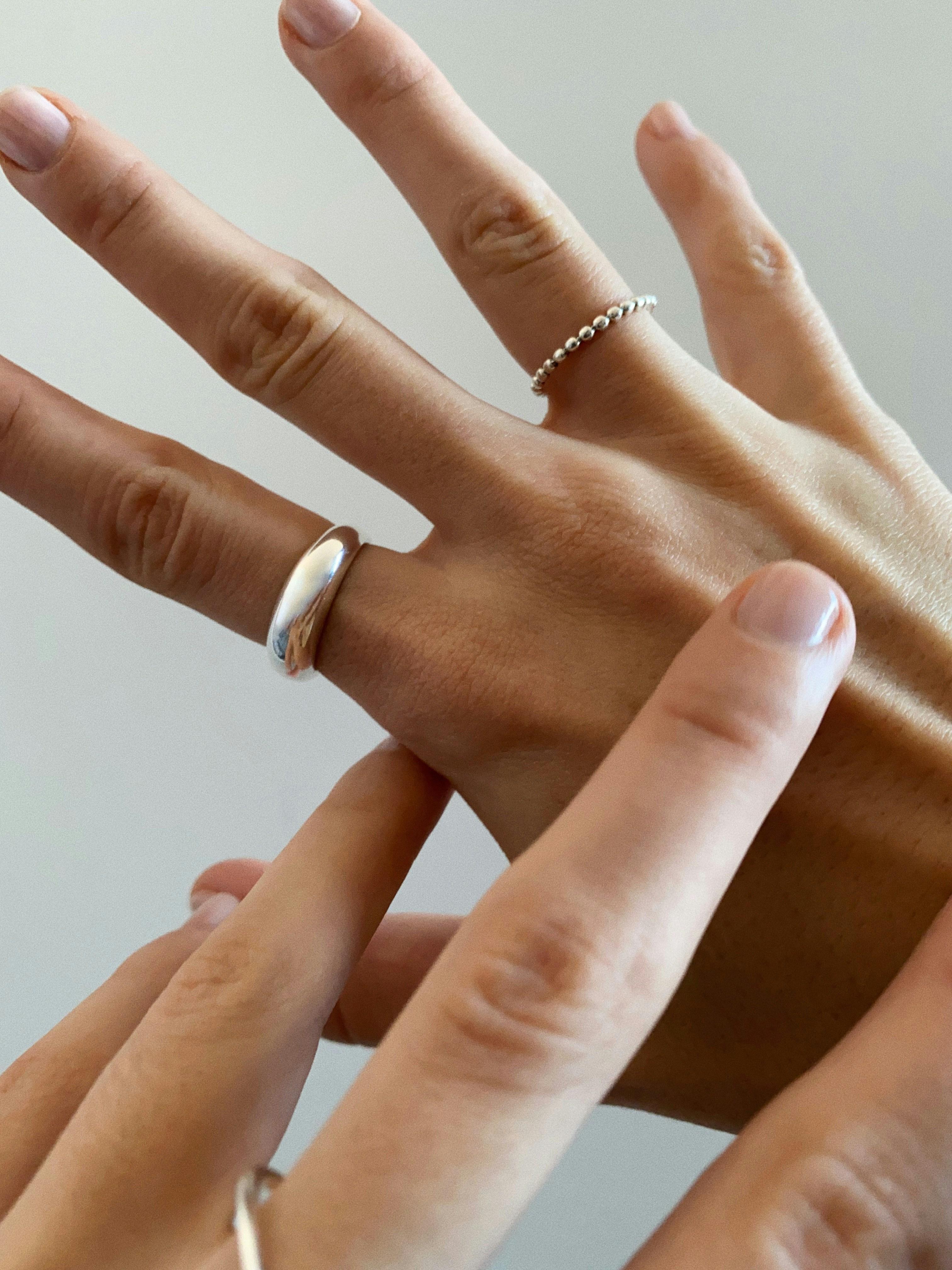 Gold signet rings stacked on elegant fingers against bright neutral background