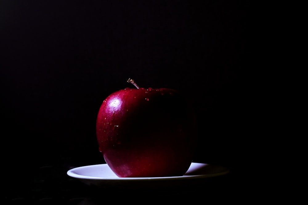 a red apple sitting on top of a white plate