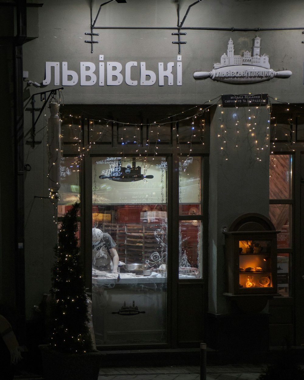 a store front with a lit up christmas tree in front of it