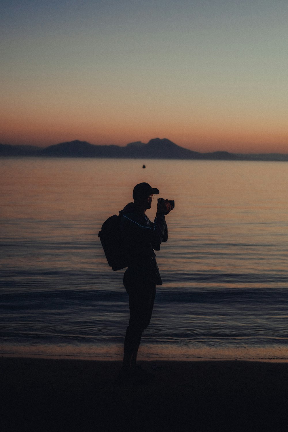 Un uomo in piedi su una spiaggia con in mano una macchina fotografica