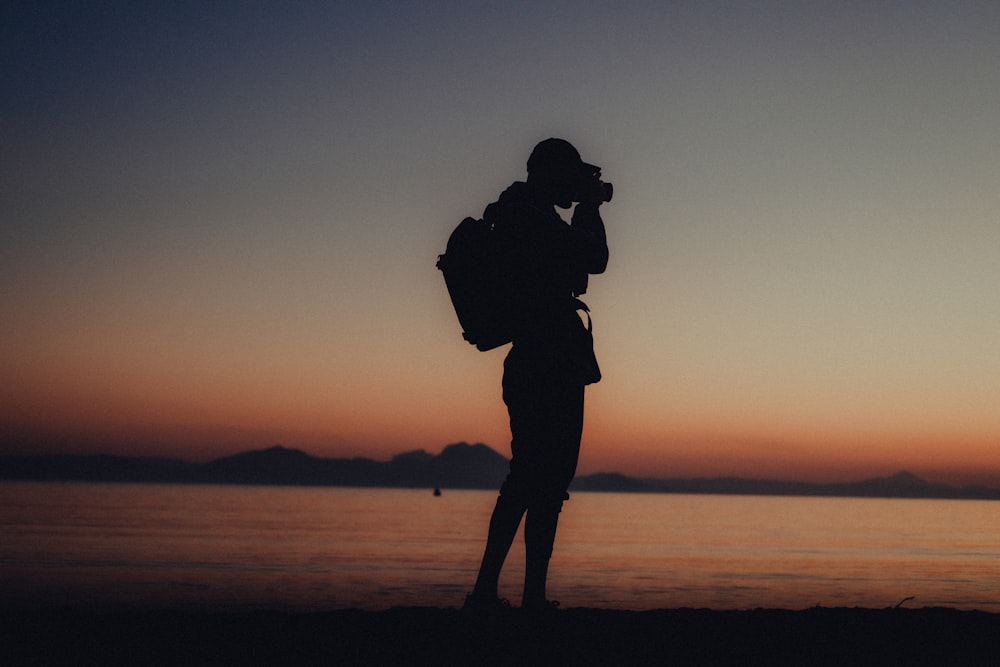 a person standing on a beach with a backpack