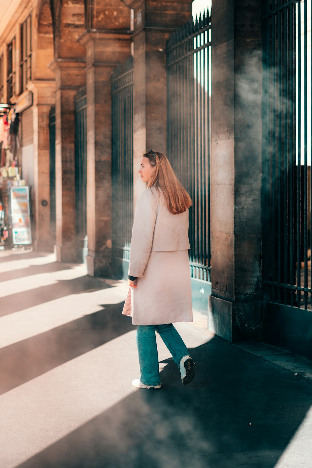 a woman walking down a street next to a tall building