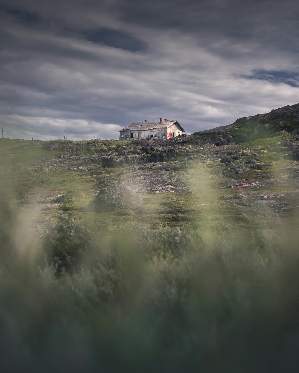 曇り空の下の丘の上に座っている家