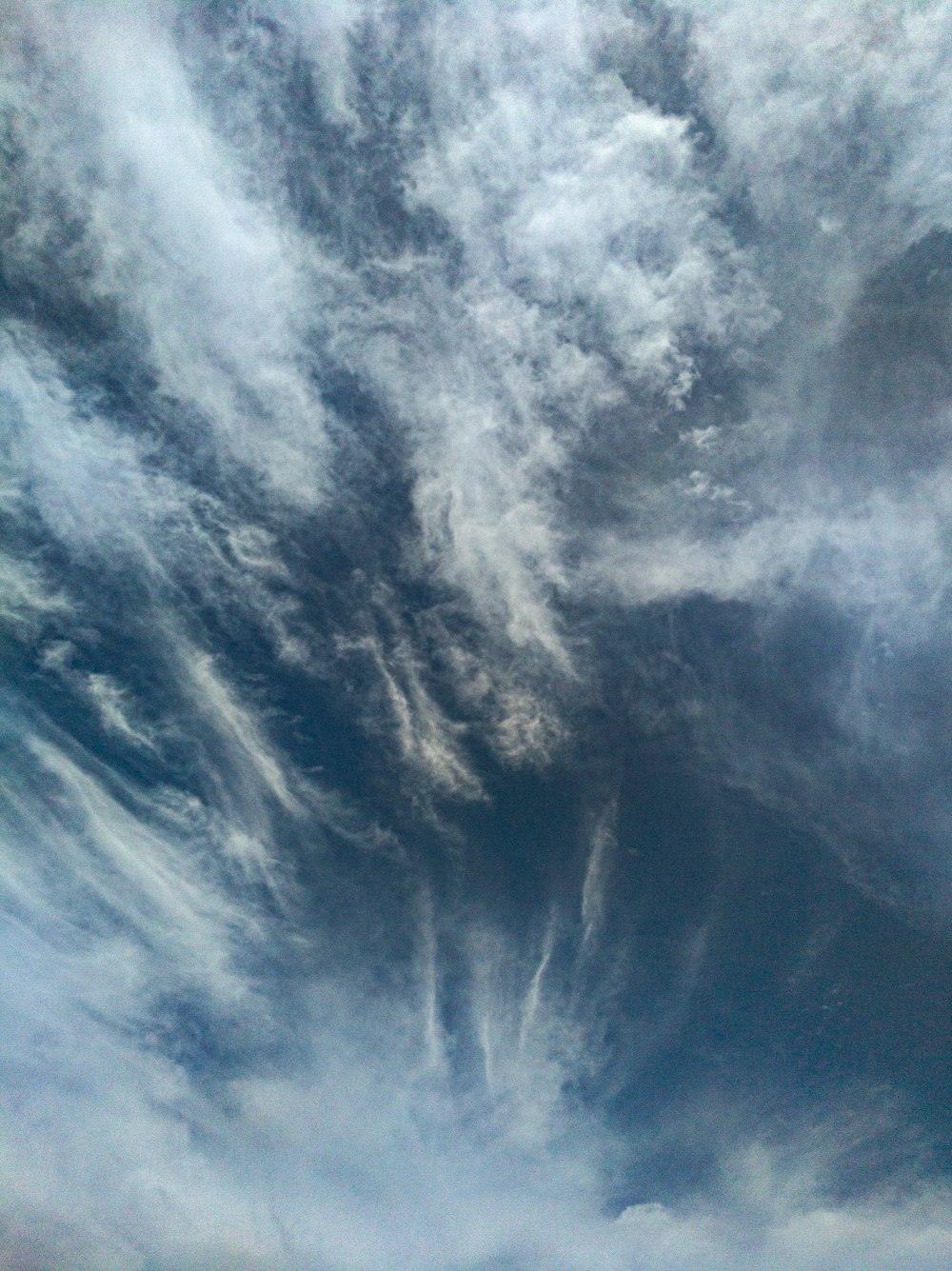 a plane flying through a cloudy blue sky