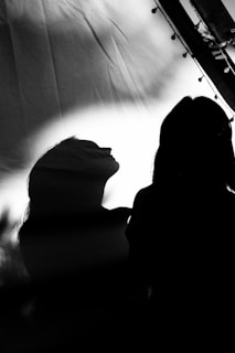 Abstract silhouette of a figure framed by harsh lighting, creating dramatic shadows.