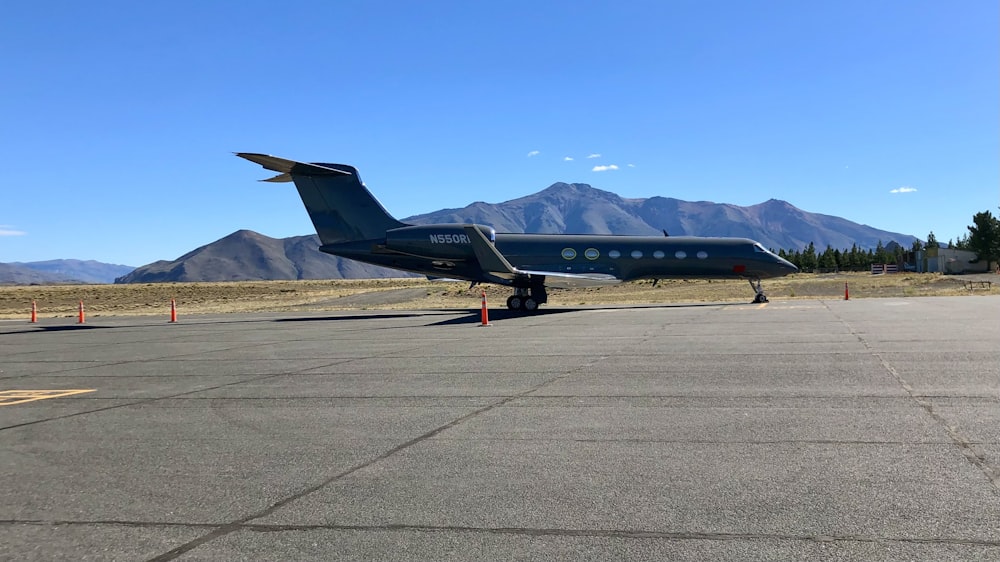 an airplane is parked on the tarmac with mountains in the background