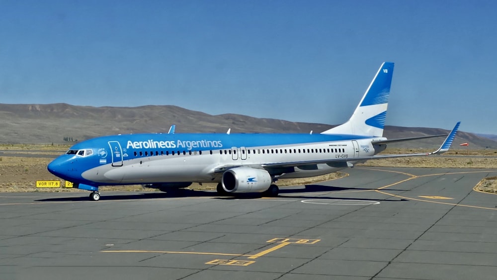 a blue and white airplane is on a runway