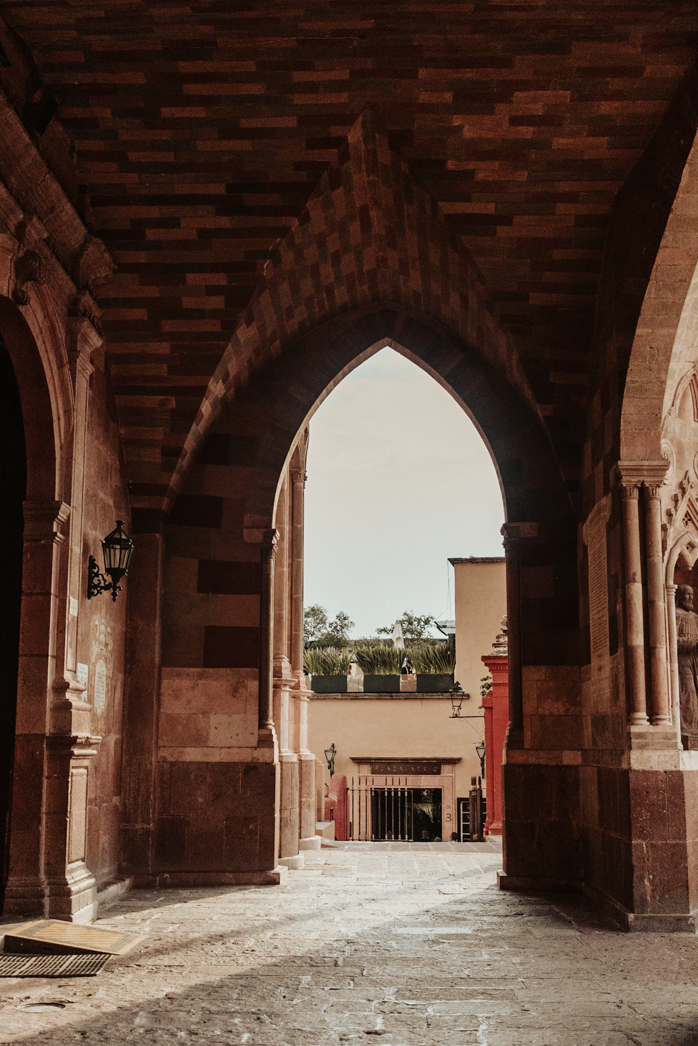 Interior gothic stone archway passage inside a colonial building in San Miguel de Allende, looking through the arch to a sunlit courtyard