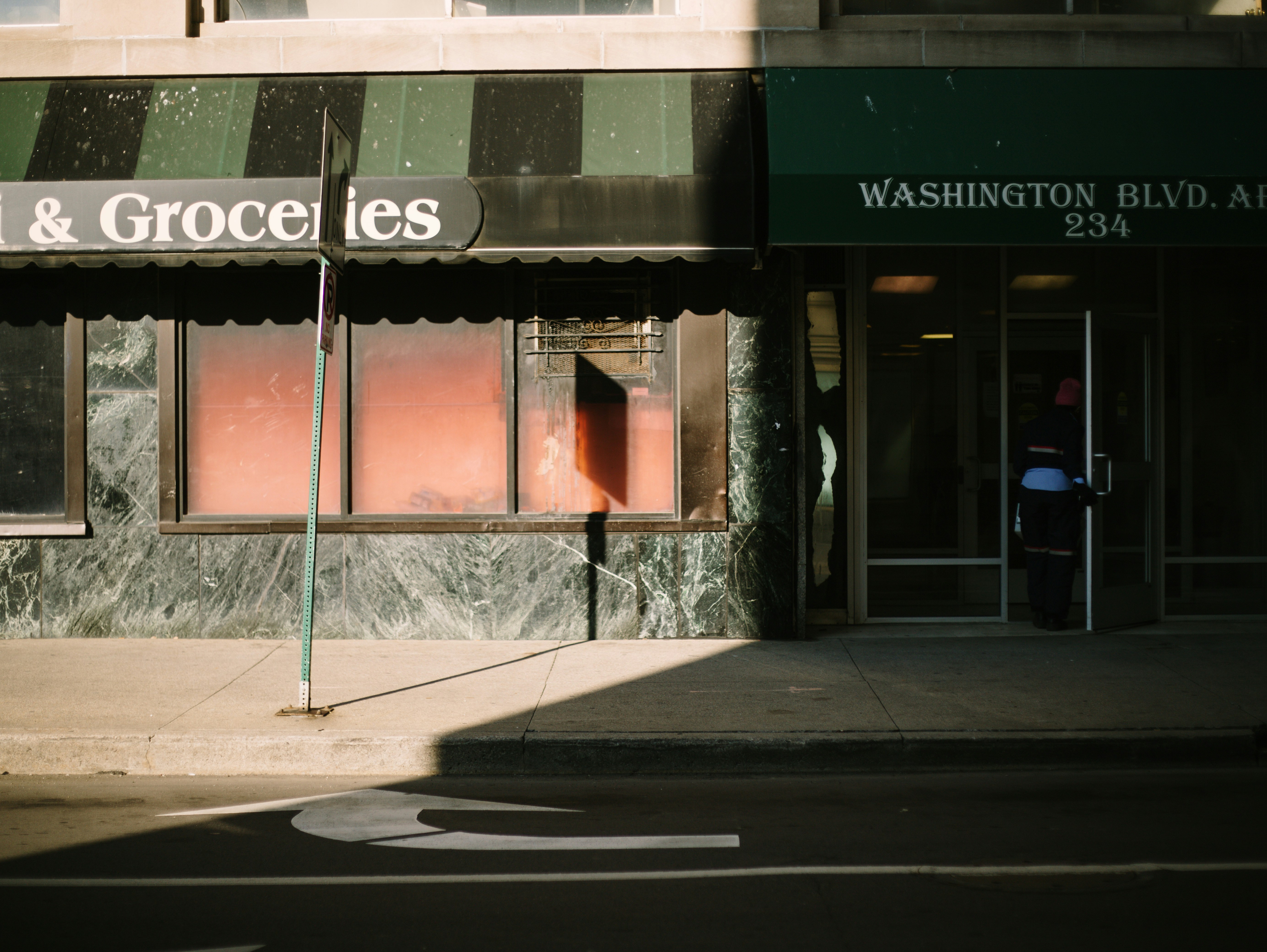 緑の日よけとその正面に看板がある建物