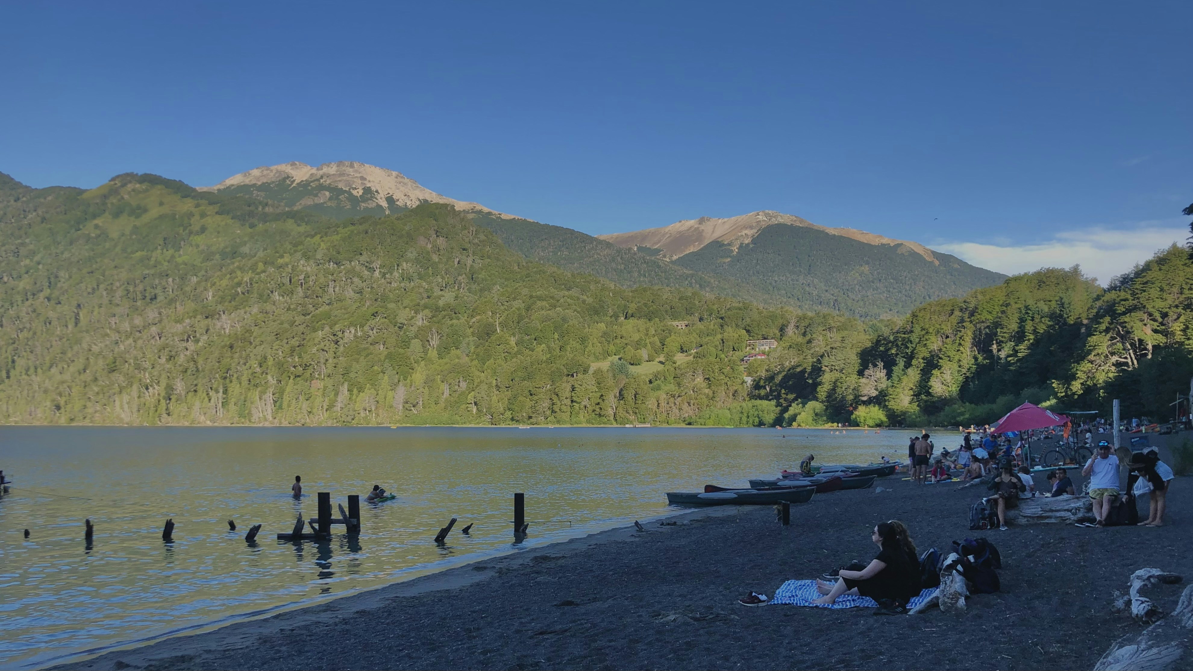 a group of people sitting on the shore of a lake