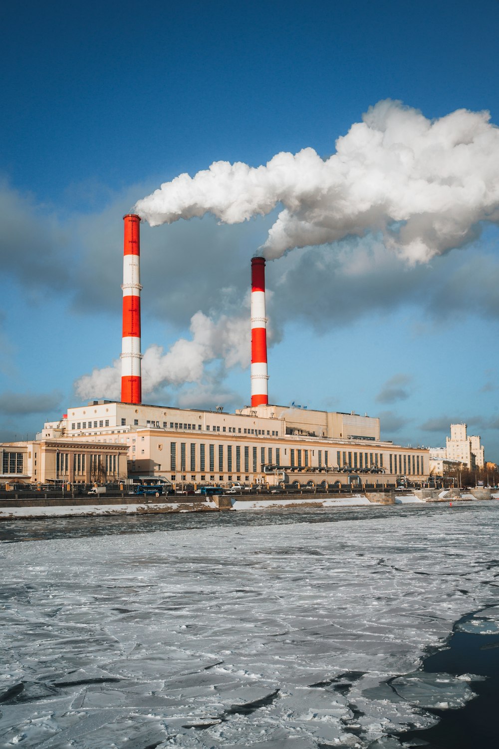 a factory with two red and white smoke stacks