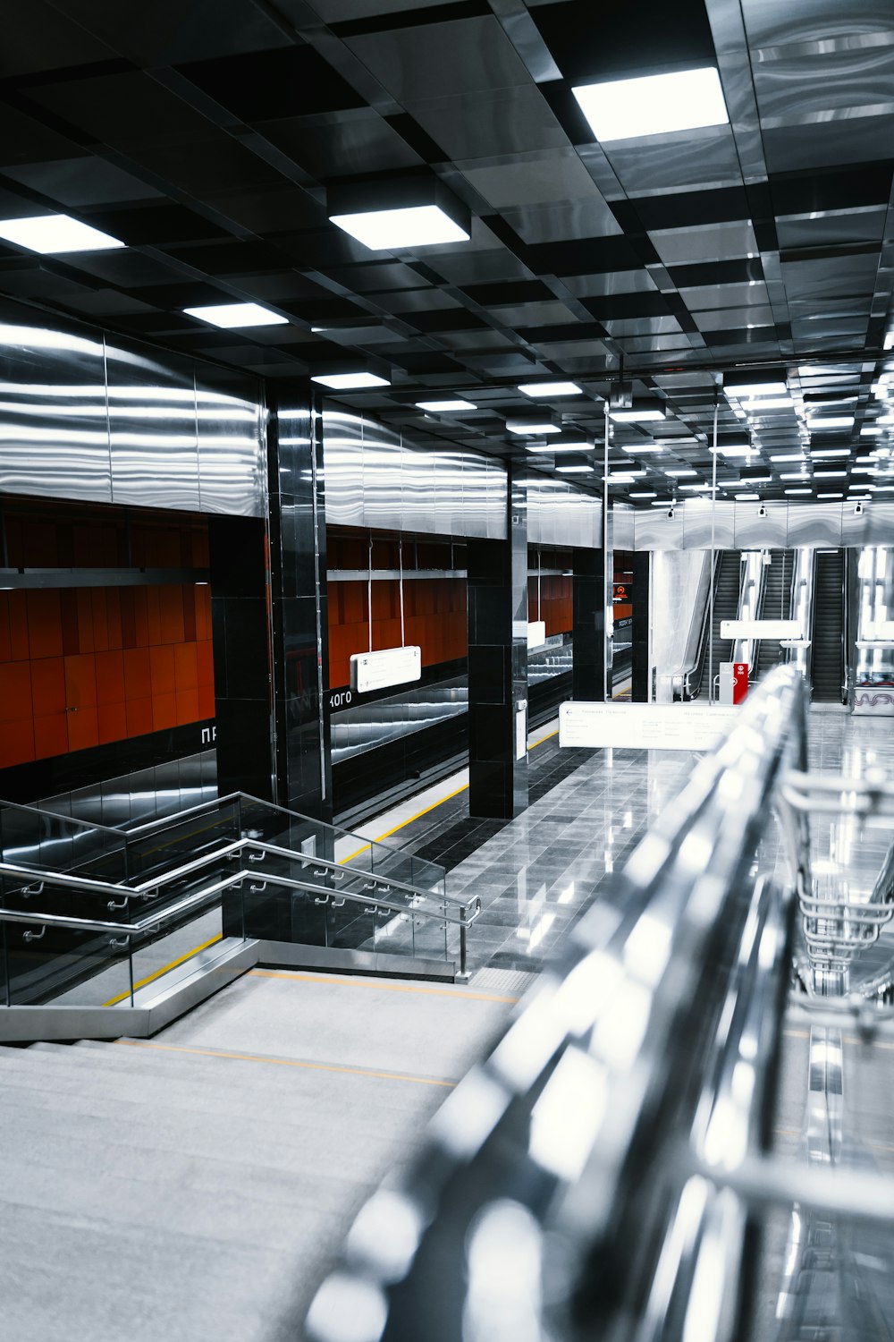 an empty subway station with escalators and railings