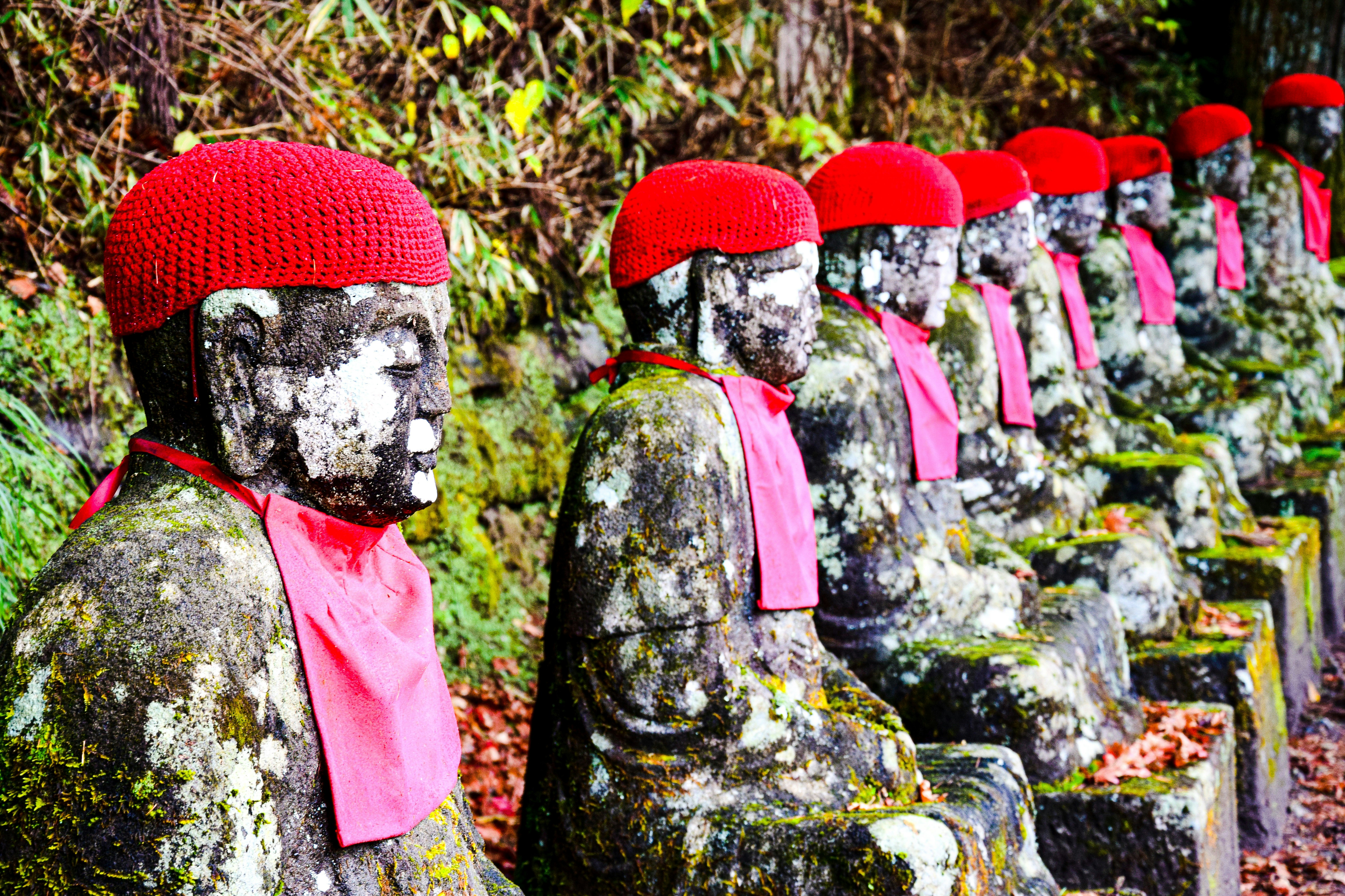 a row of statues with red hats and scarves, 