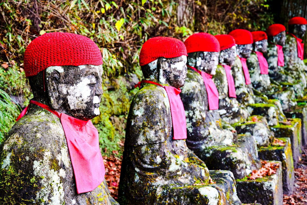 a row of statues with red hats and scarves,