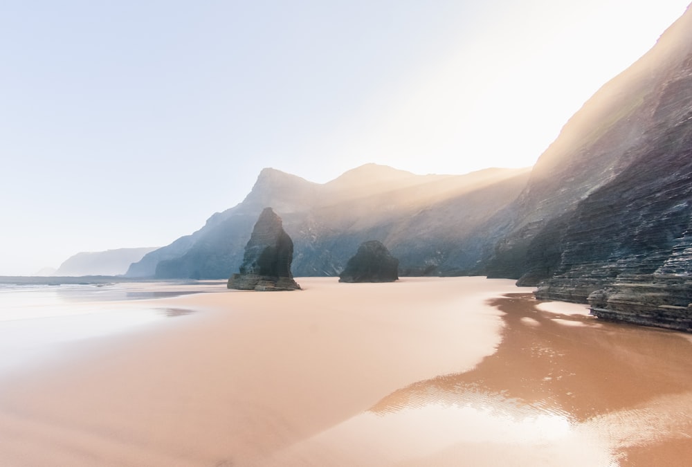 a sandy beach with mountains in the background