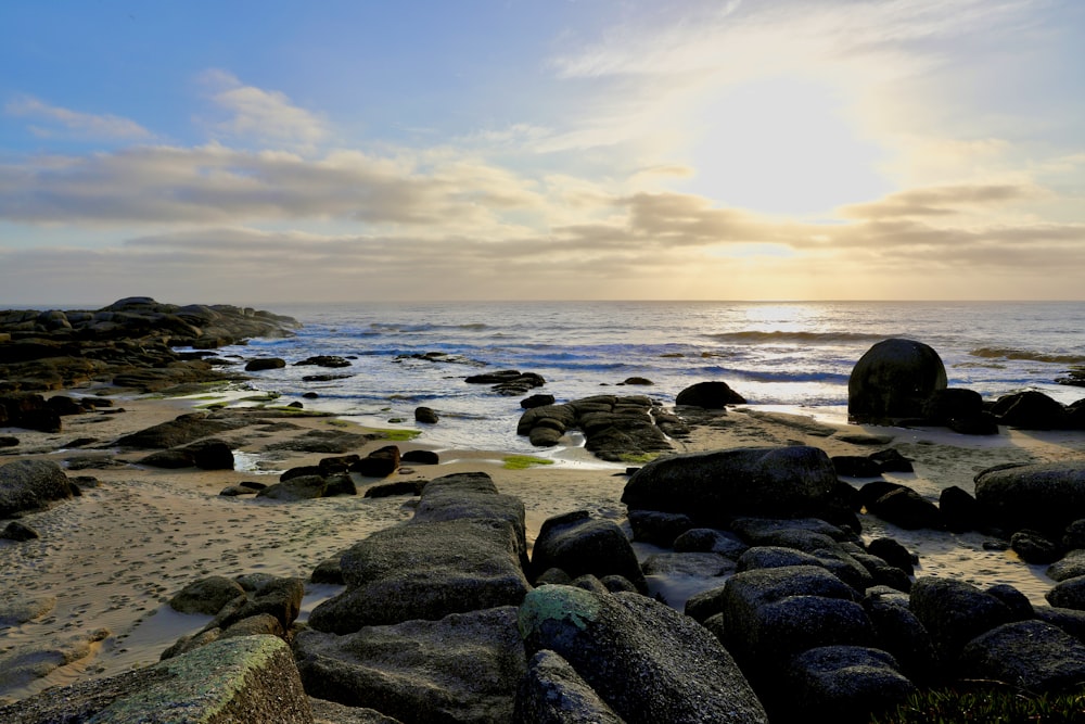 the sun is setting over a rocky beach