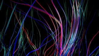 Vibrant swirling colorful lines twisting gracefully across a dark background.