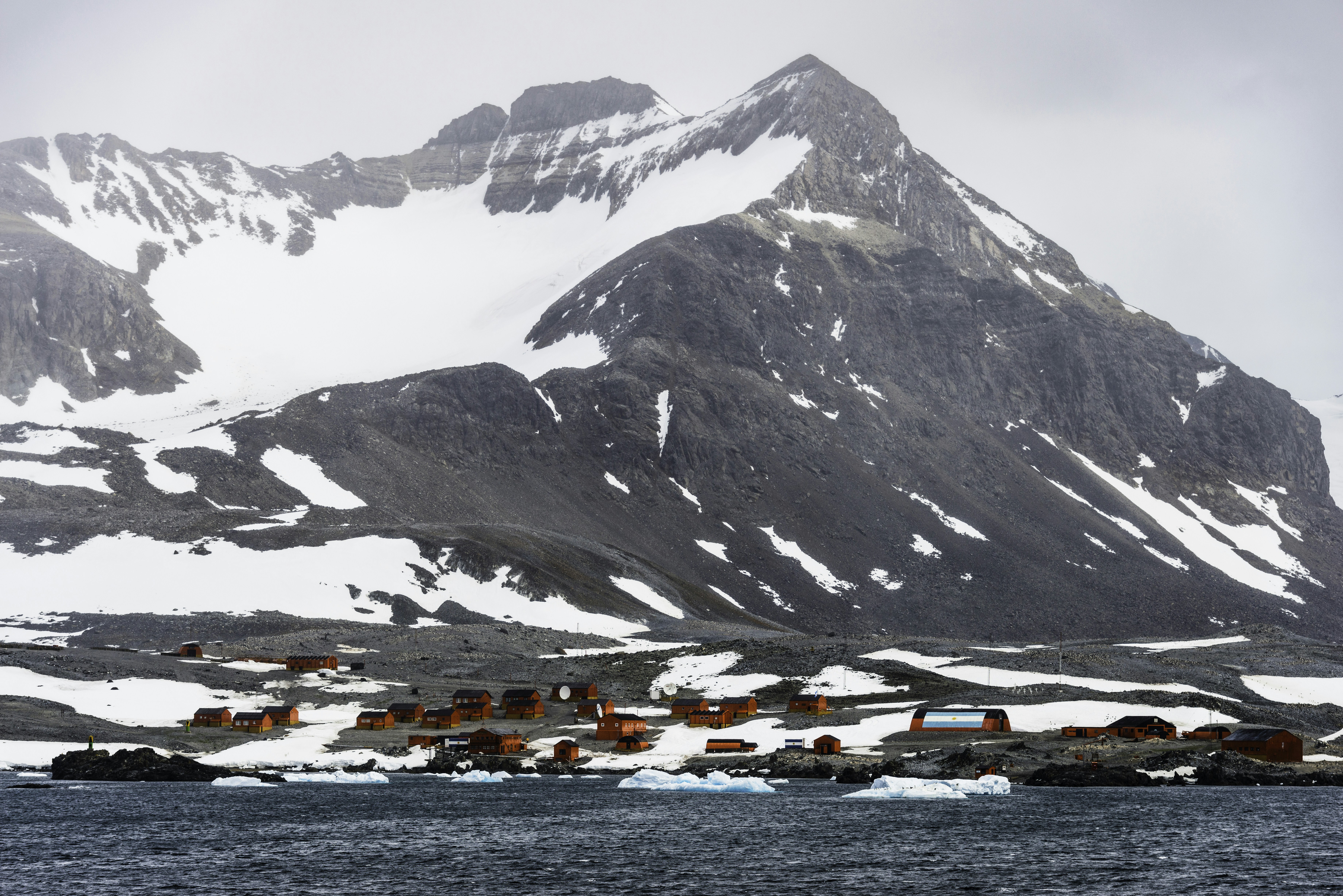 a snow covered mountain with a village in the foreground, The Argentinian "Esperanza" Base at Hope Bay on the Antarctic Peninsula