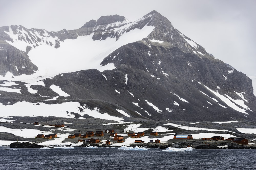 uma montanha coberta de neve com uma aldeia em primeiro plano