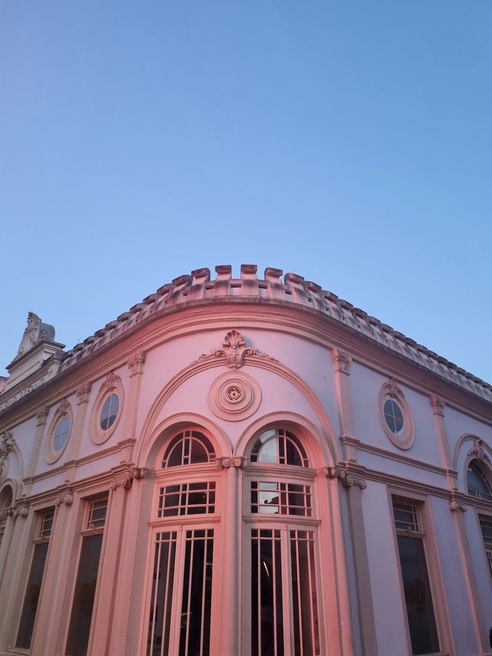 Ein rosa Gebäude mit einer Uhr auf der Spitze