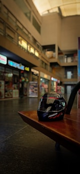 A sleek motorcycle helmet resting on a wooden bench with a blurred road background.