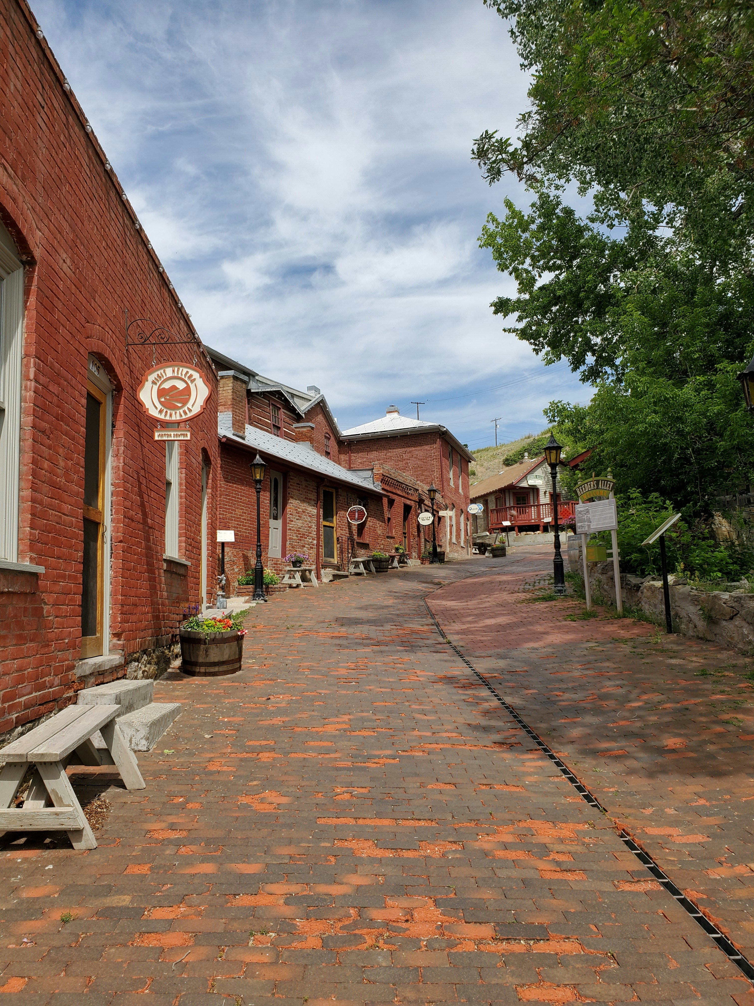 a brick street lined with benches next to a building