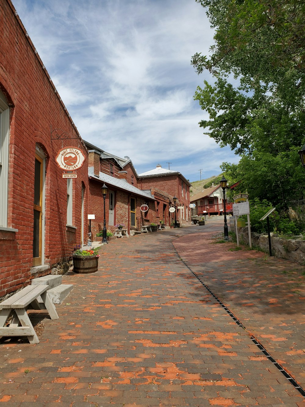 a brick street lined with benches next to a building