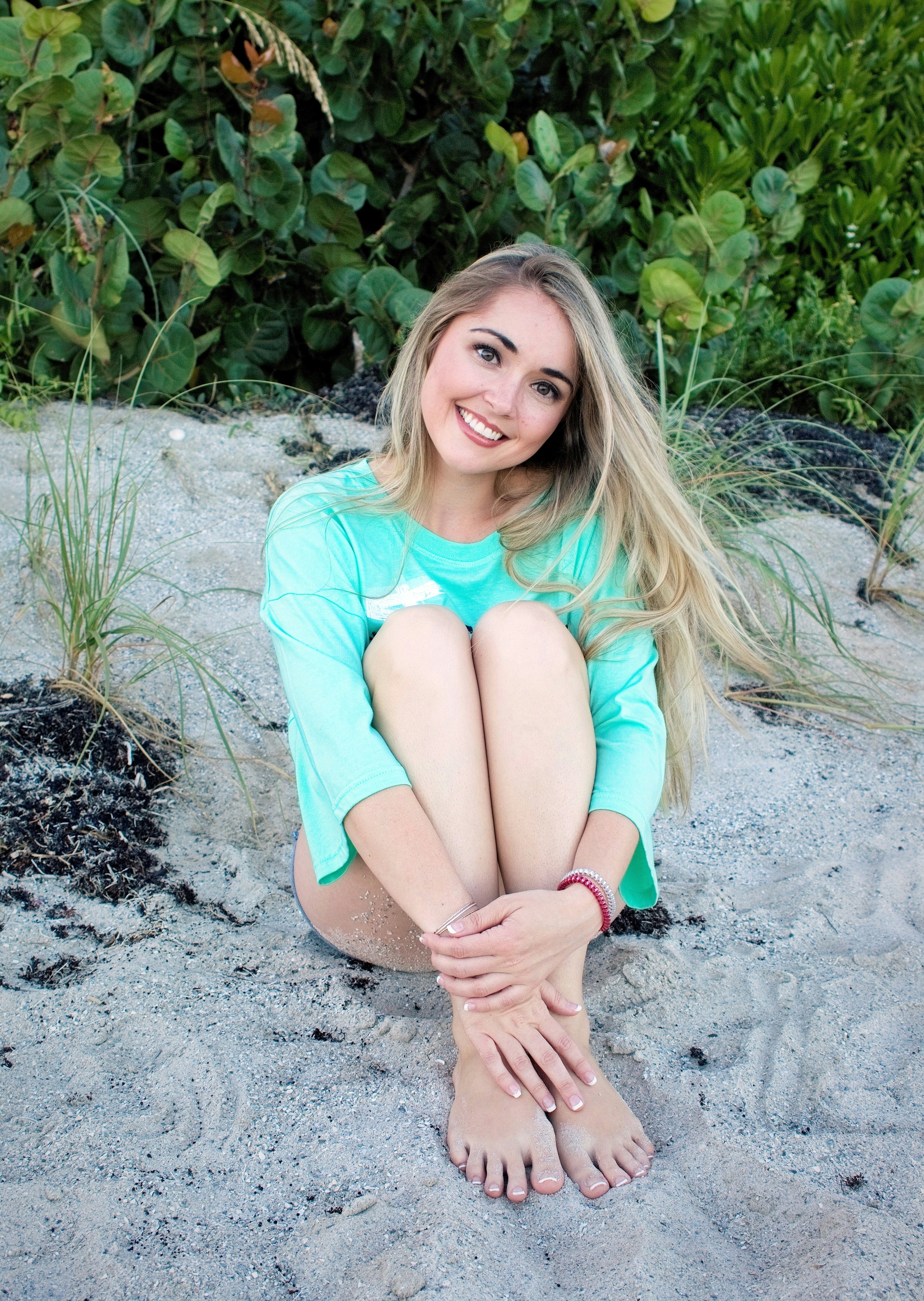 a woman sitting on the sand with her hands on her knees