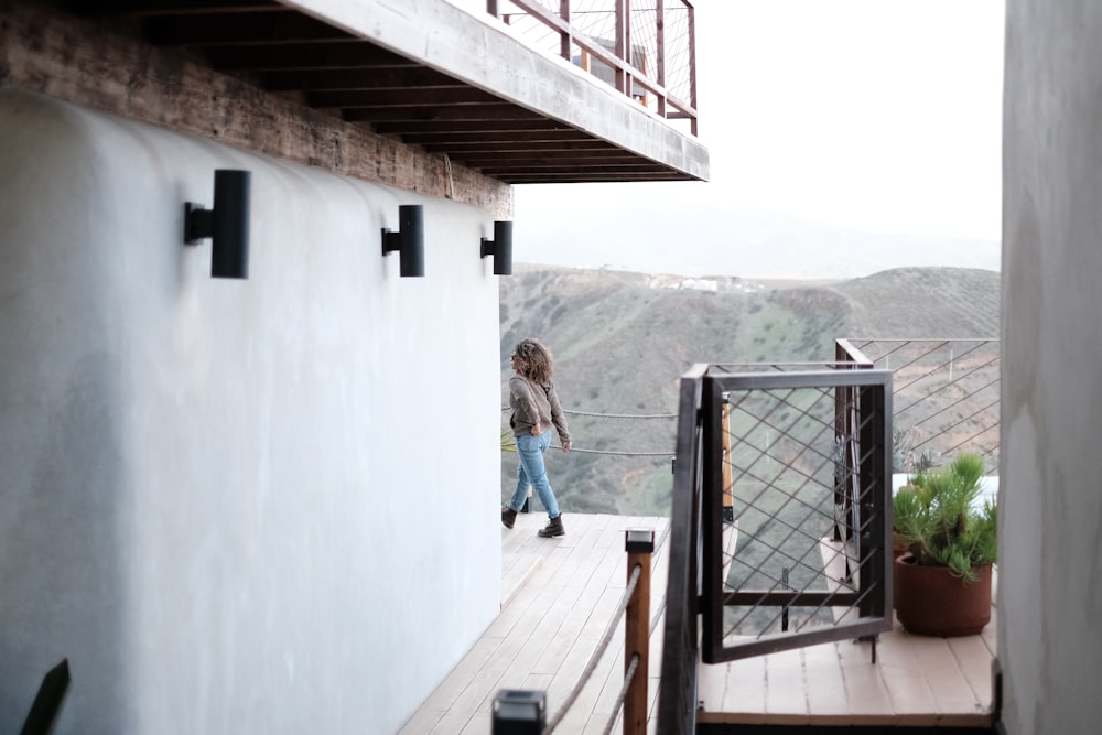 a woman walking down a wooden deck next to a building