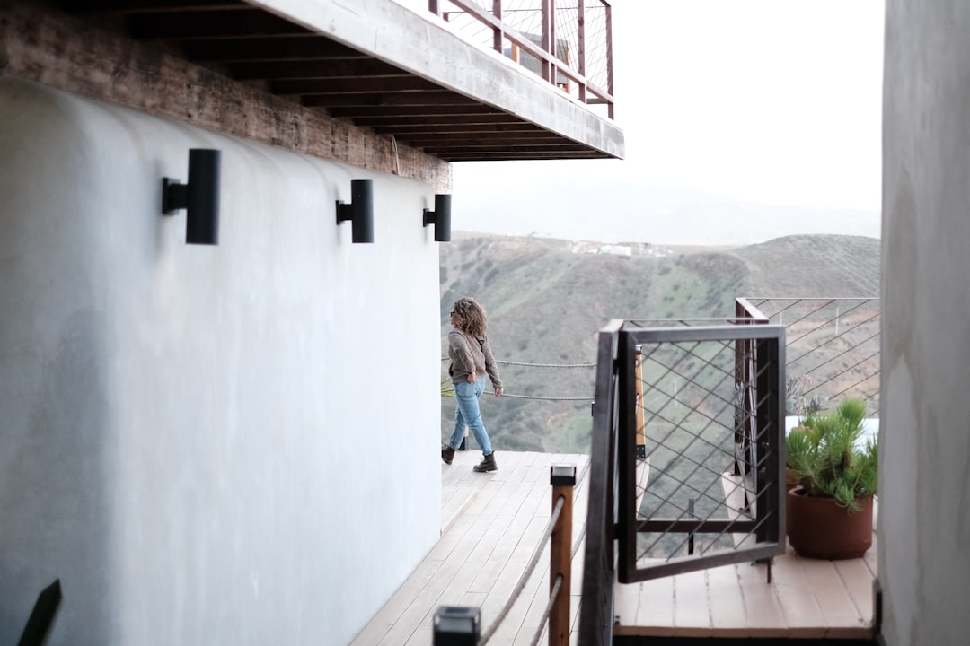 a woman walking down a wooden deck next to a building, Walking through a luxury hotel property.