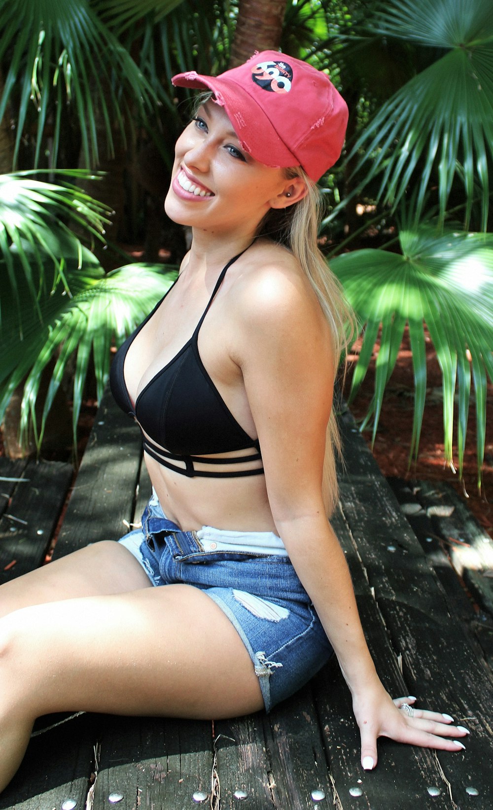 a woman sitting on a wooden bench wearing a pink hat